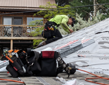 Cal Coast Roofing roofer working on a Woodside roof with tools in foreground.